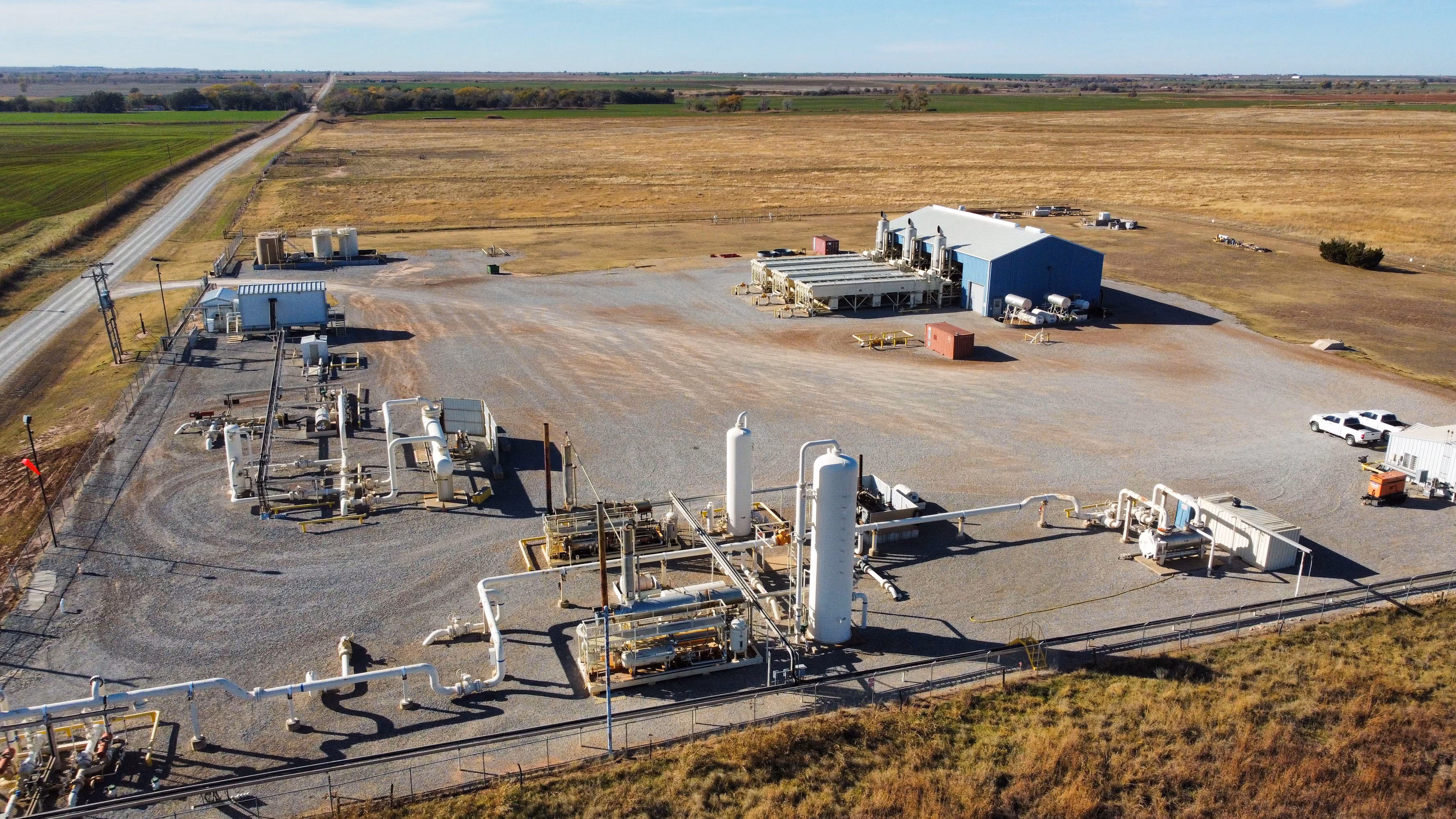 Aerial view of an industrial plant with storage tanks and pipes in a rural area.