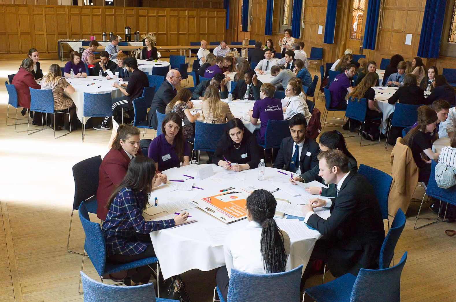 Photo of people sat around round tables in a conference hall