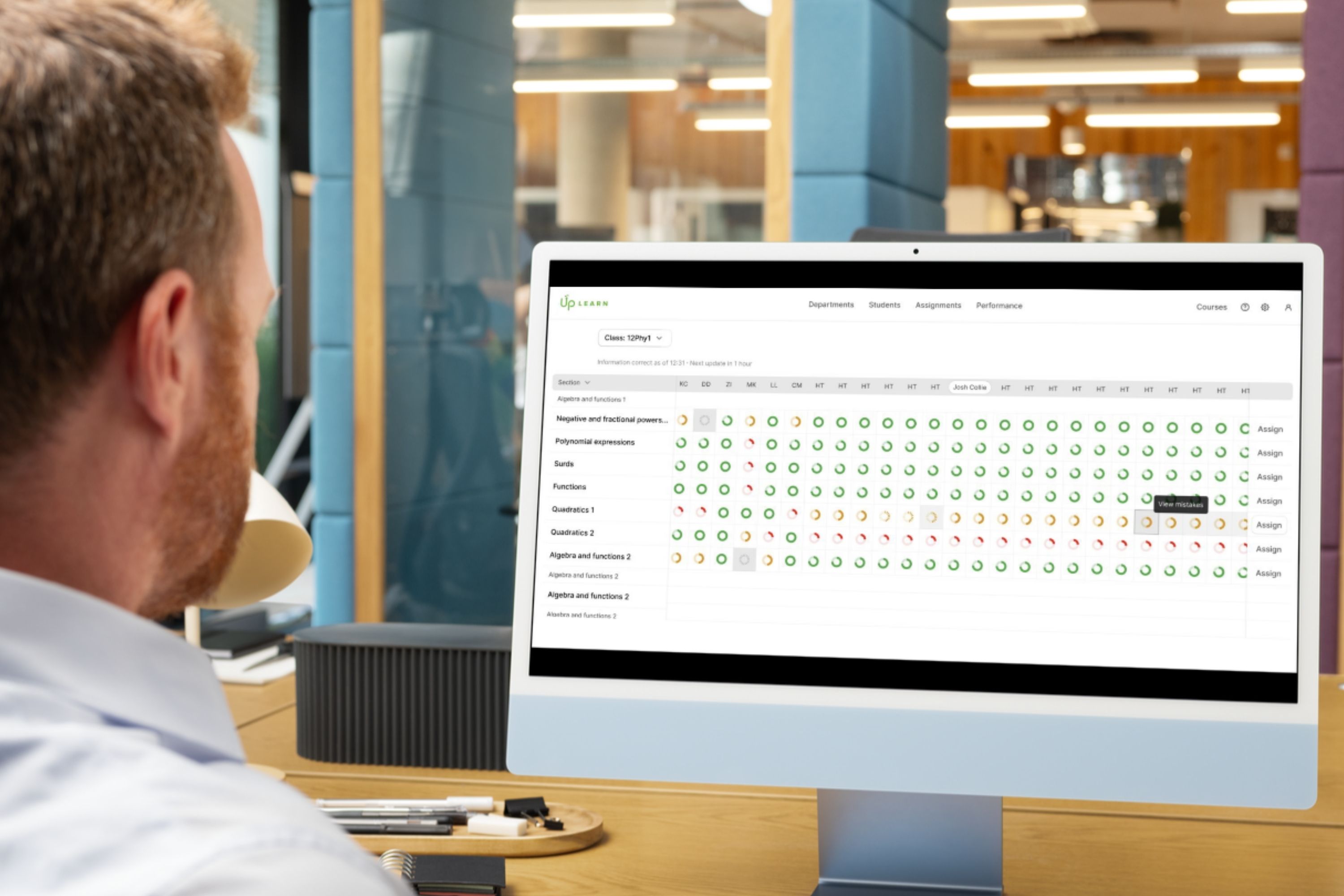 Photo of a man sat in front of a computer screen that's showing Up Learn's Performance view within the teacher dashboard