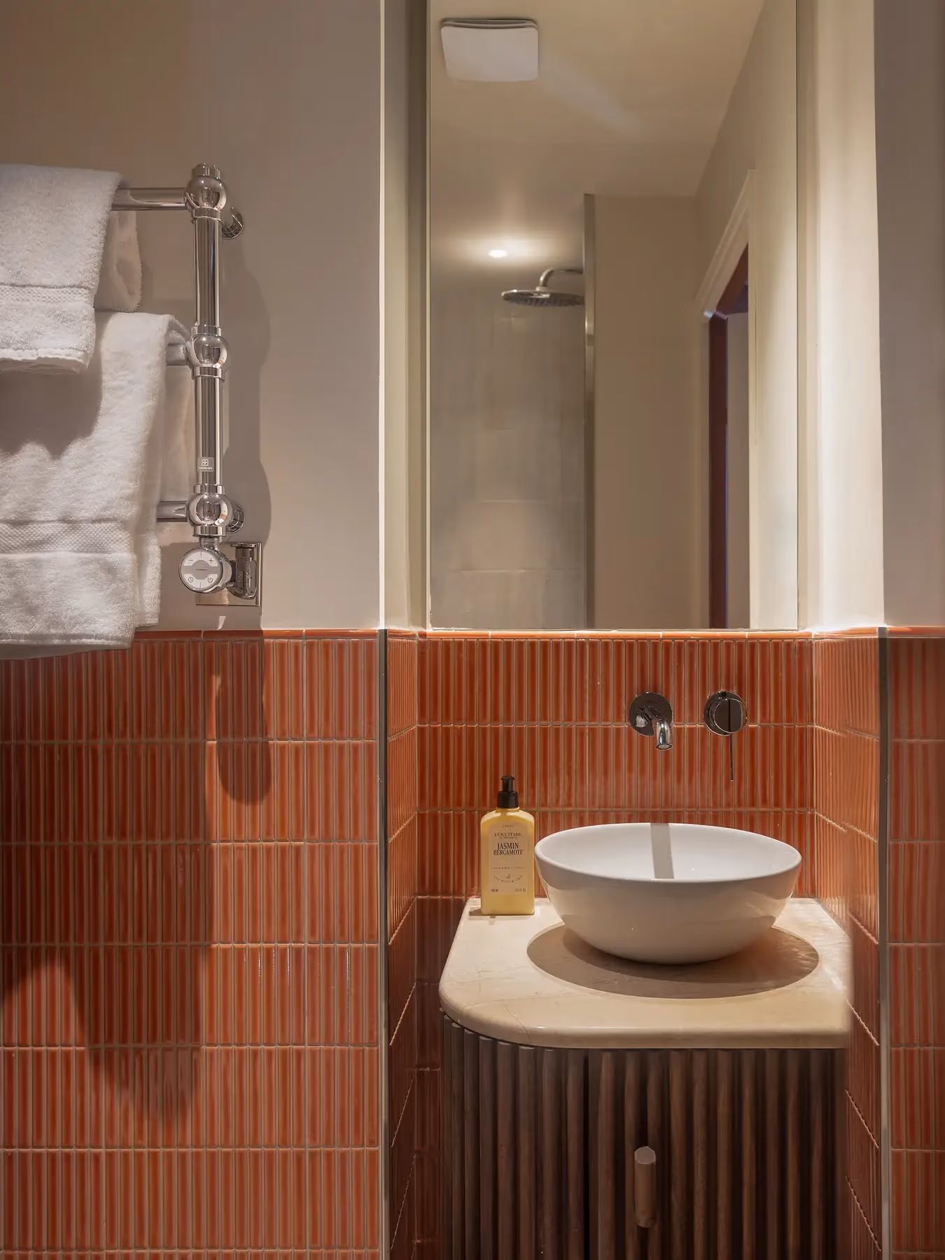 Salle de bain aux carreaux terracotta avec vasque ronde et miroir mural.