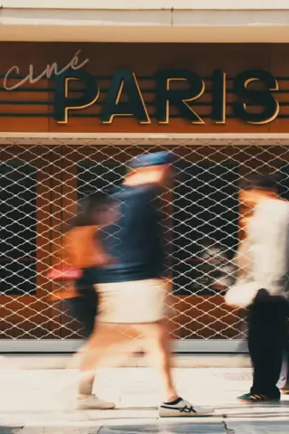 Photo en mouvement flouté de piétons devant l'enseigne "Ciné Paris", cadrée avec bordures noires.