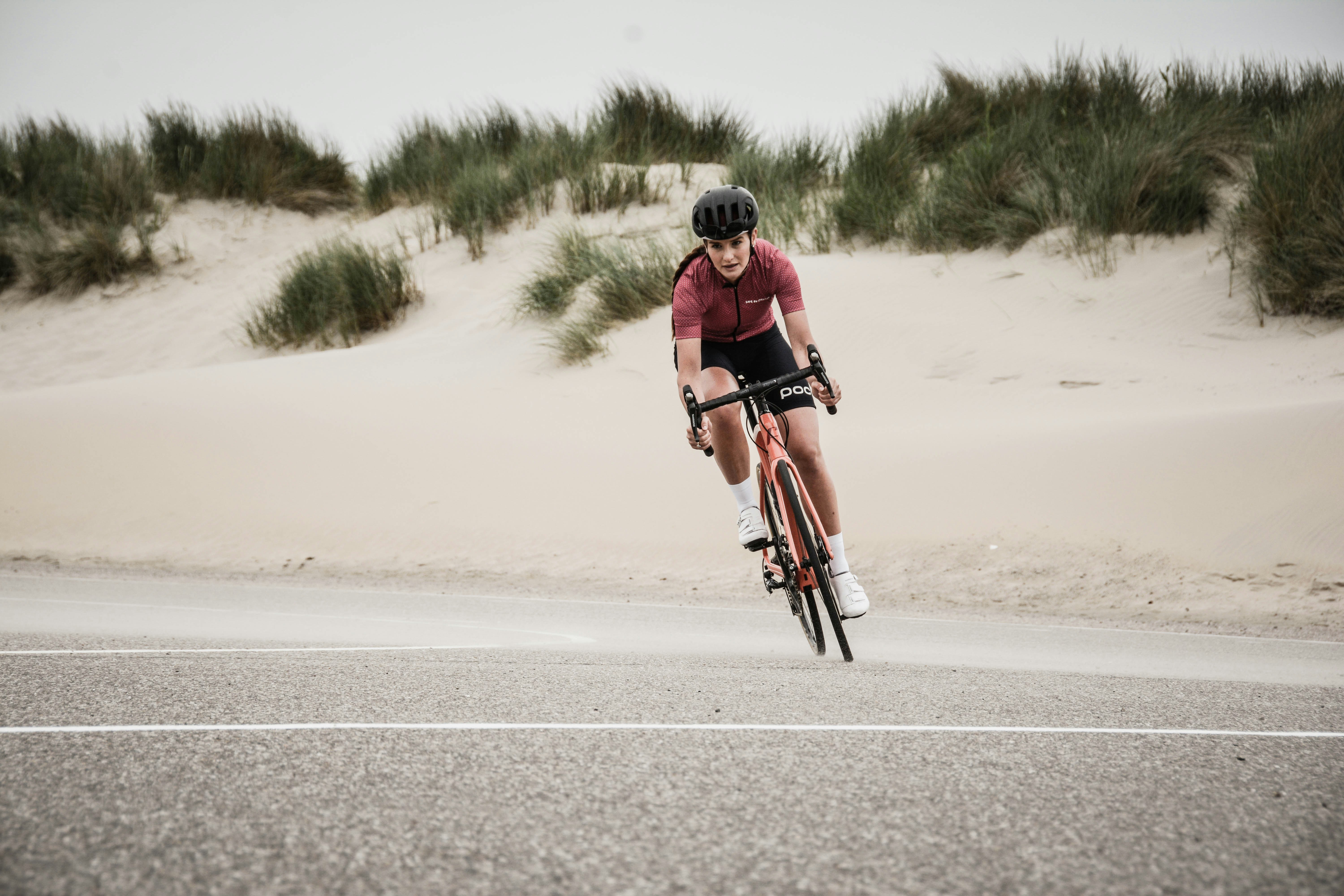 A cyclist riding a road bike along an open coastal road