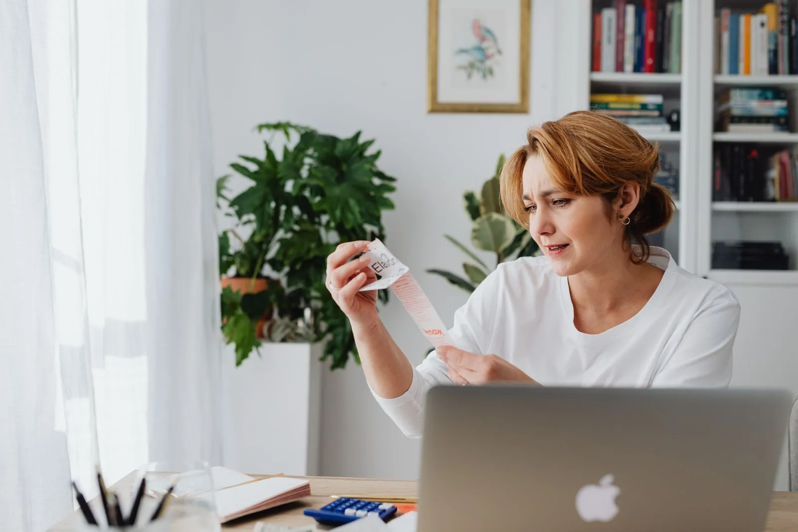 A person at home reviewing a receipt while filing personal taxes on a laptop