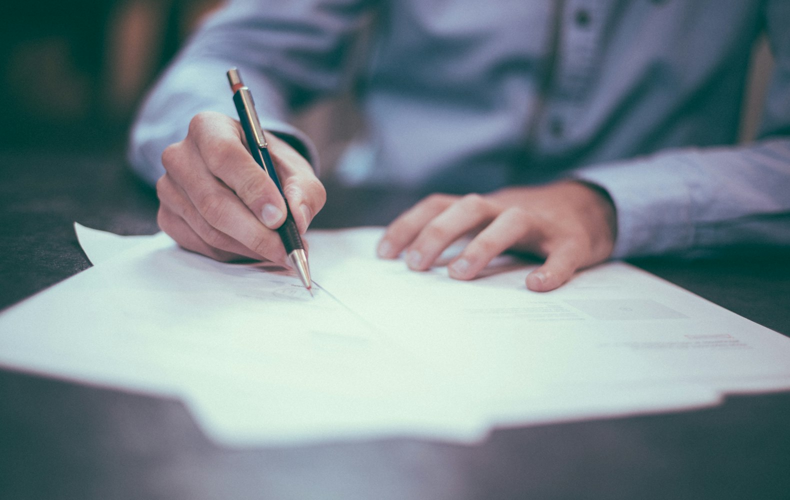 Person filling out and signing tax paperwork