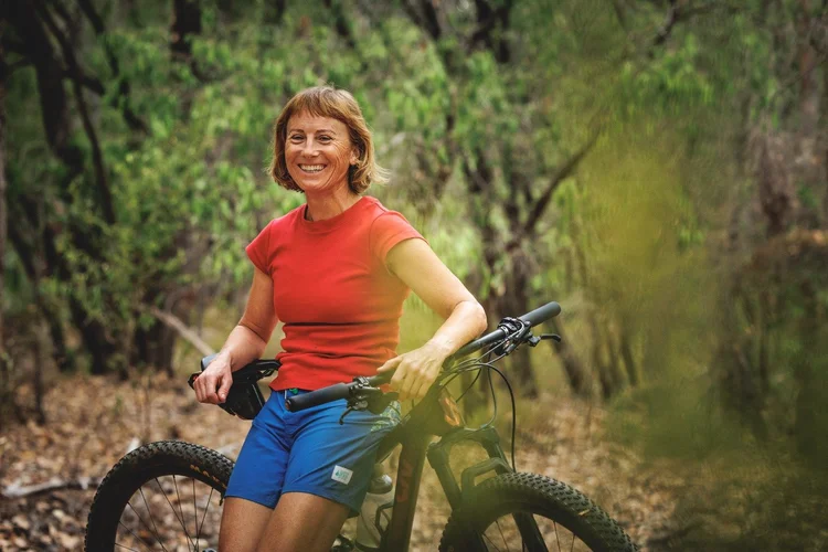 Rebecca sitting on a bike in the forest
