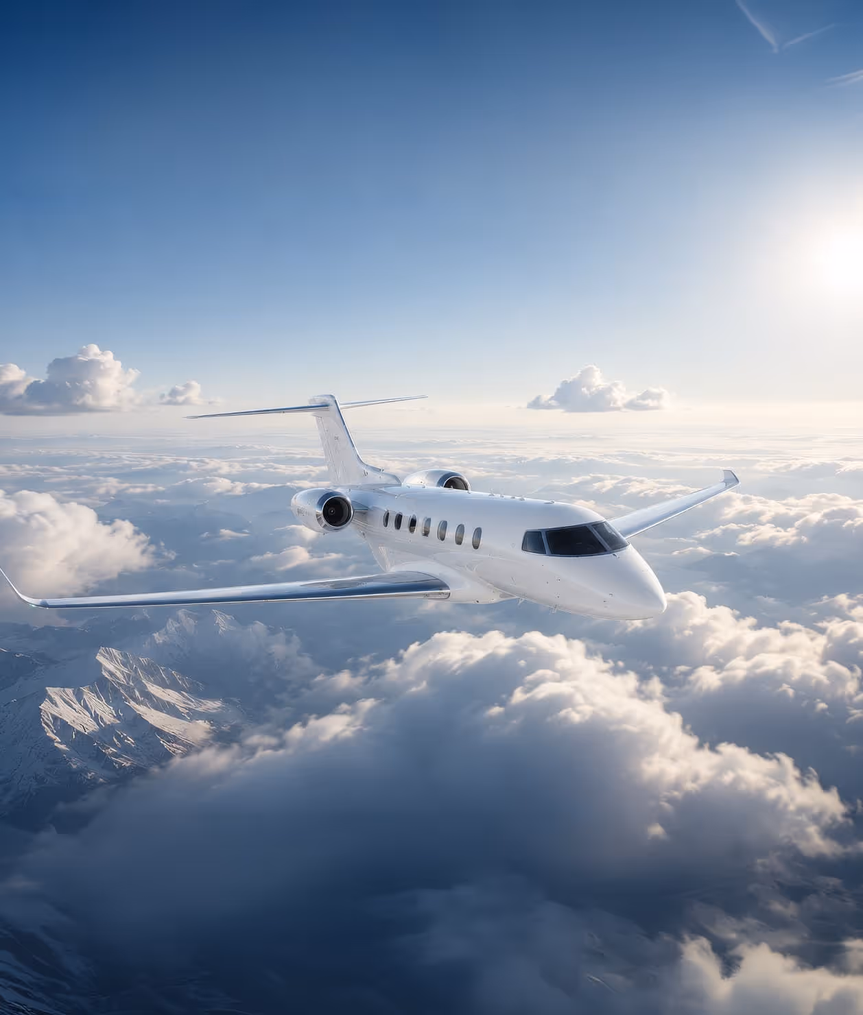 White private jet flying above clouds with mountains below and sun on the right.
