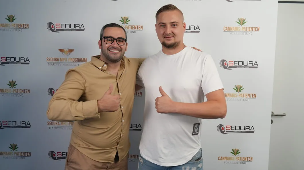 Zwei Männer lächeln und zeigen Daumen hoch vor einer Wand mit Cannabis-Patienten- und Sedura-Logos.
