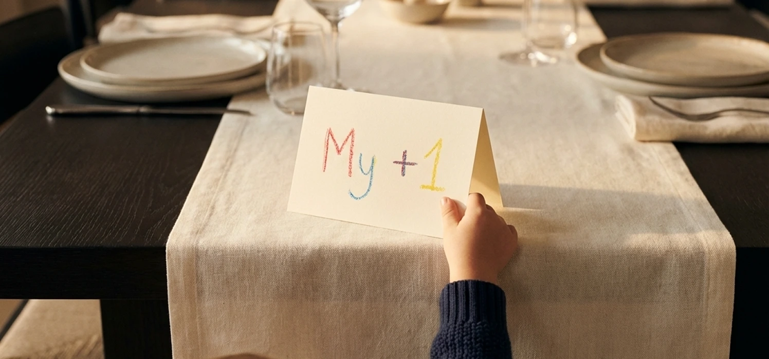 Hand holding a card on a dining table that reads 'My +1' in colorful letters.