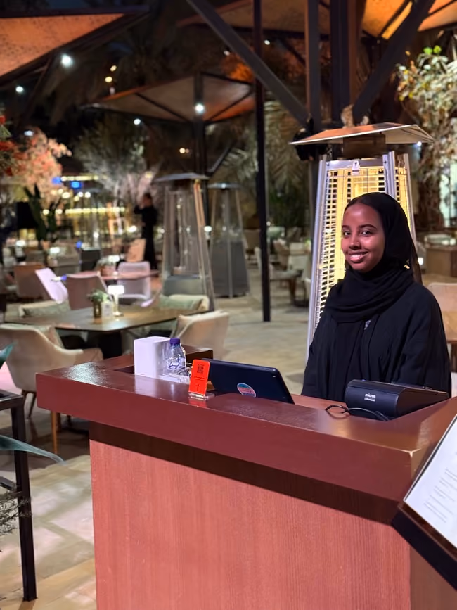 Two Melas hosts standing at a curved timber welcome desk