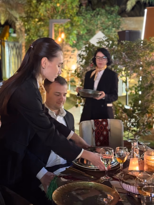 waiter pouring a drink into a guest's cup