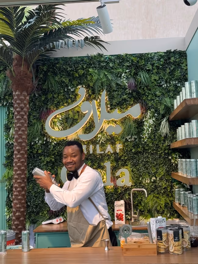 Barista pouring latte art into a takeaway cup behind the bar