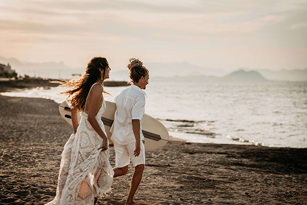 Brautpaar-Shooting auf Mallorca. Das Hochzeitspaar läuft bei Sonnenuntergang Hand in Hand in Richtung Meer.