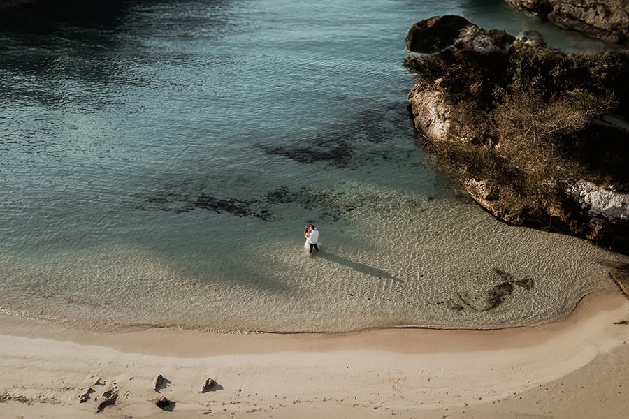 Drohnenfoto eines Hochzeitspaaren, dass im Wasser einer mallorquinischen Bucht steht.