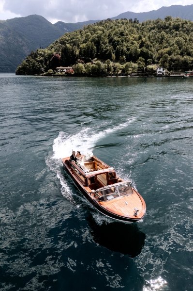 Bride and groom cruising across Lake Como in a classic wooden boat after their destination wedding