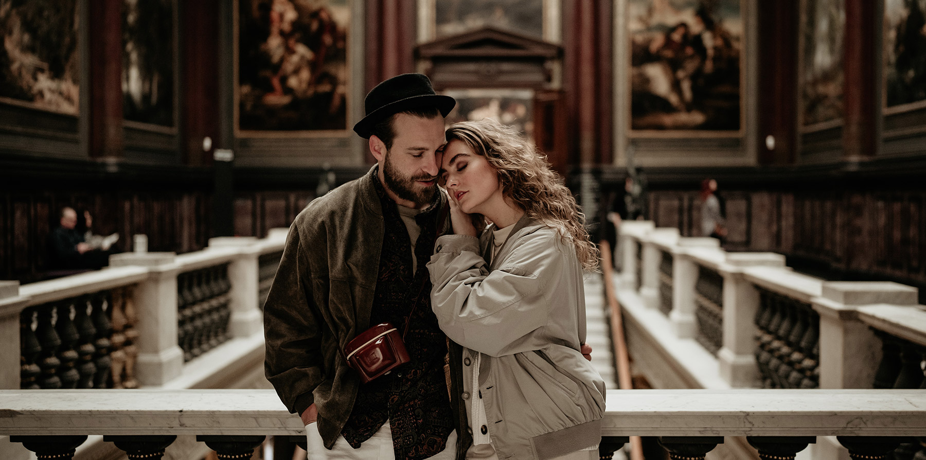Ein verliebtes Paar im Boho-Stil steht für ein Couple Shooting vor einer alten Kunstgalerie.