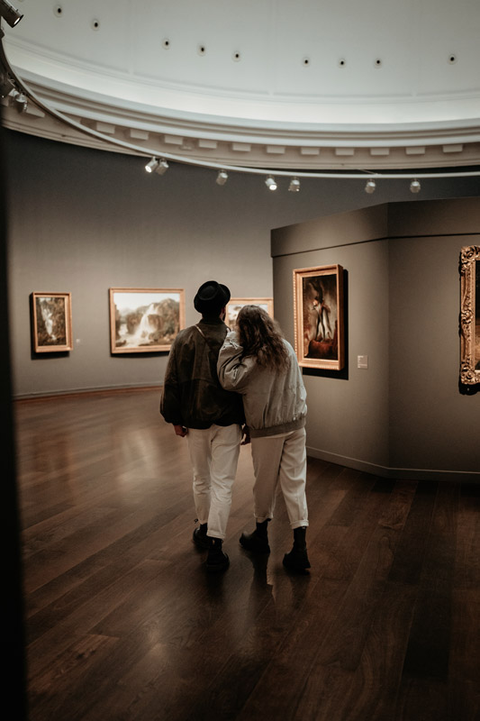 Ein junges Paar schlendert während eines Fotoshootings durch eine alte Kunstgalerie.