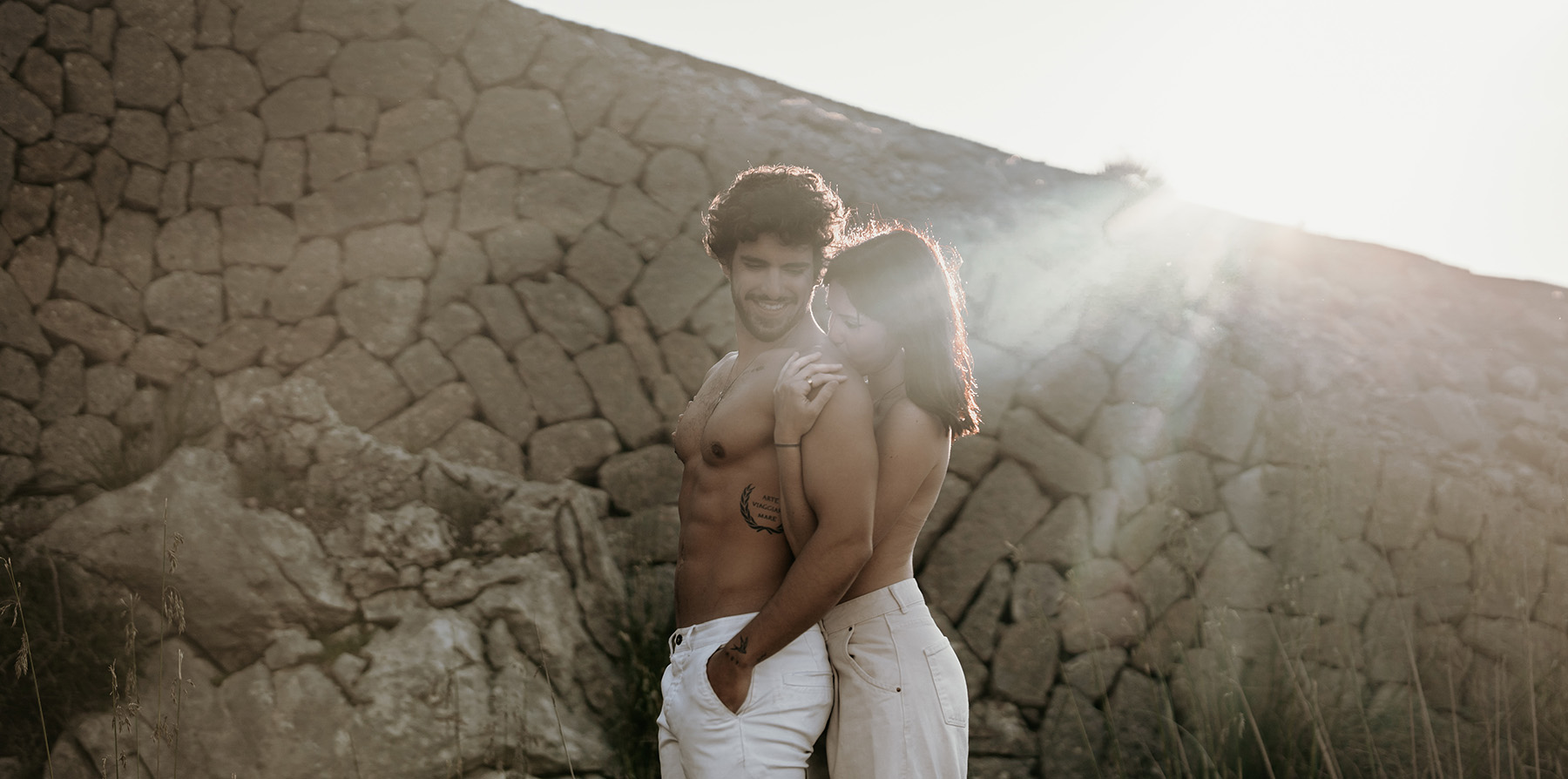 Pärchen Shooting auf Mallorca. Ein Paar umarmt sich auf einer Steinmauer des Gebirges Tramuntana.