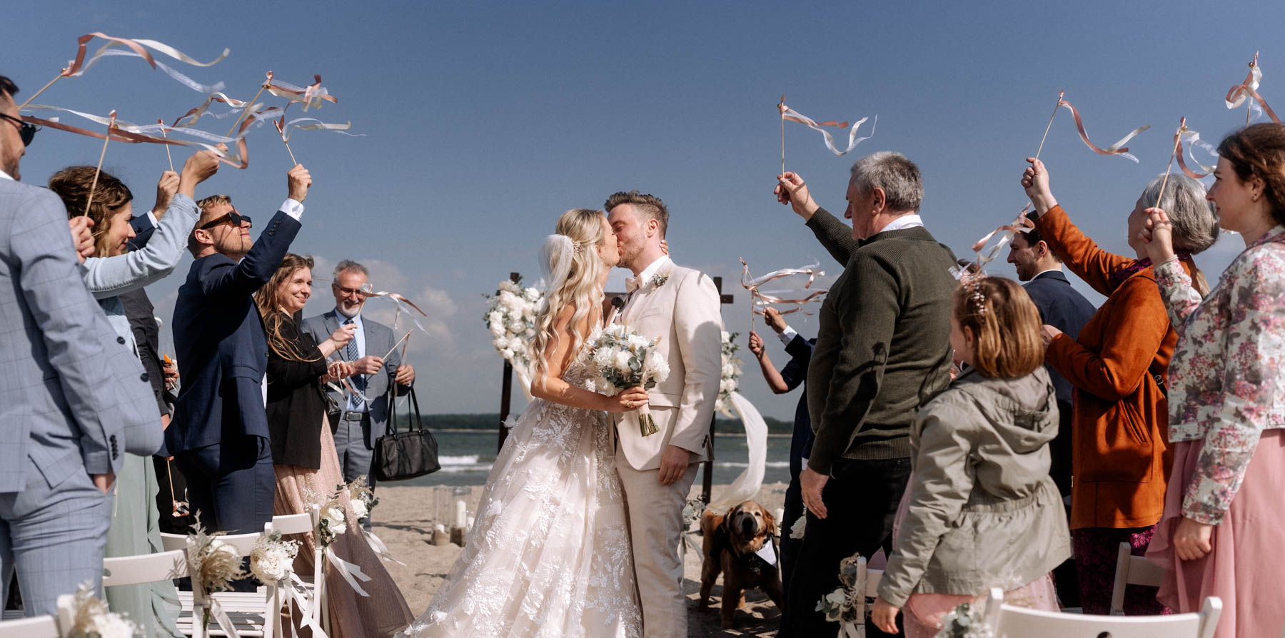 Bridal couple kissing at the end of beach wedding ceremony