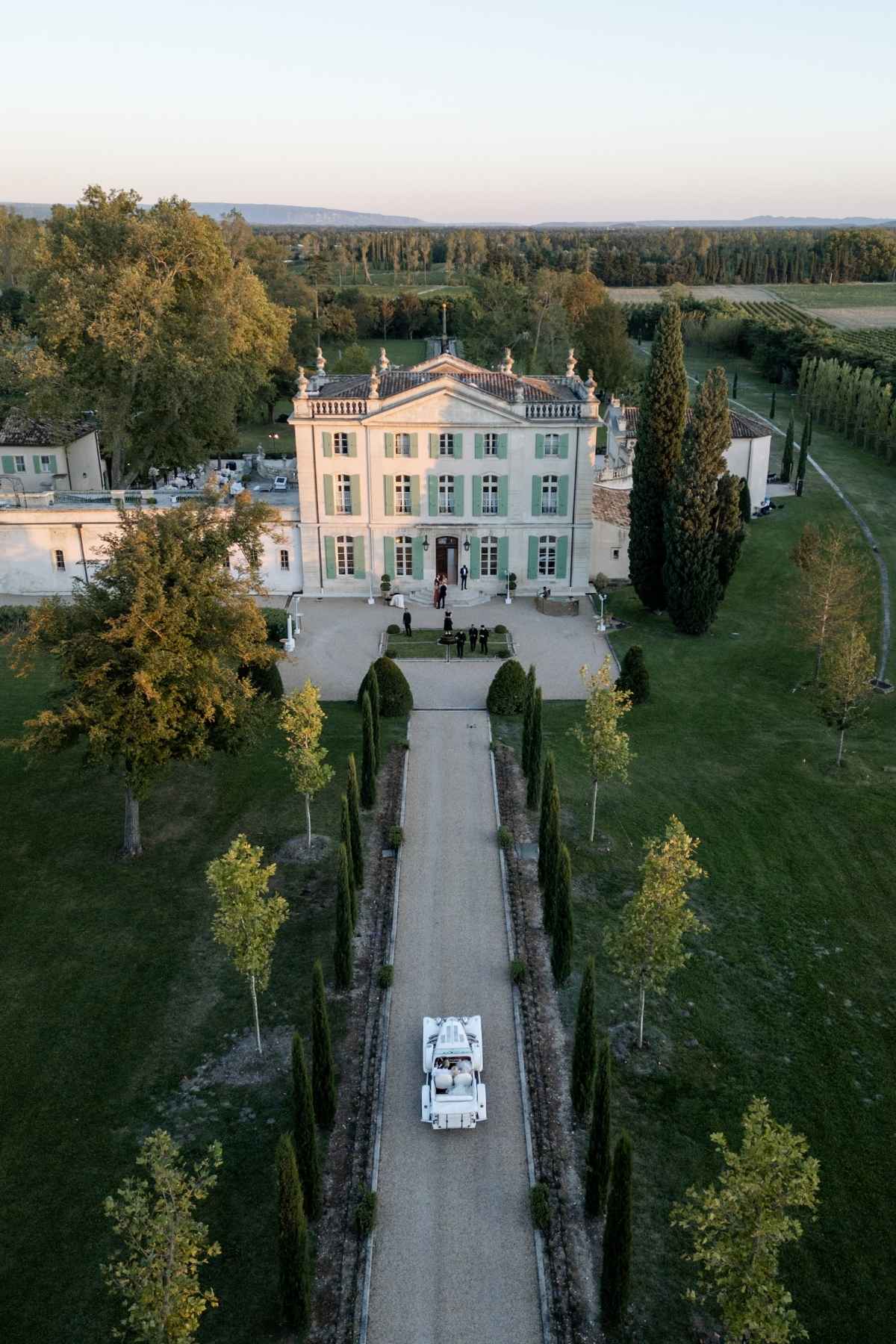 Aerial view of a bride and groom arriving at their luxury destination wedding château in Provence, France with a vintage car
