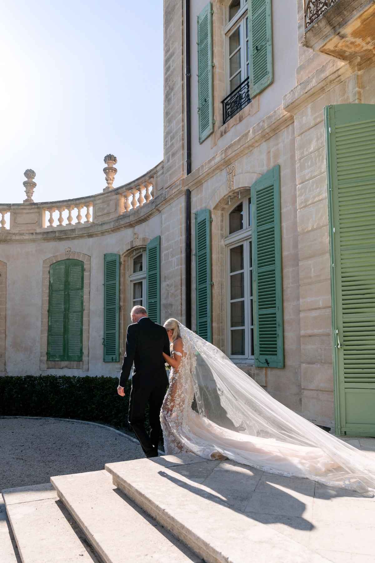 Entrance of bride with her father, walking beside a historic French château