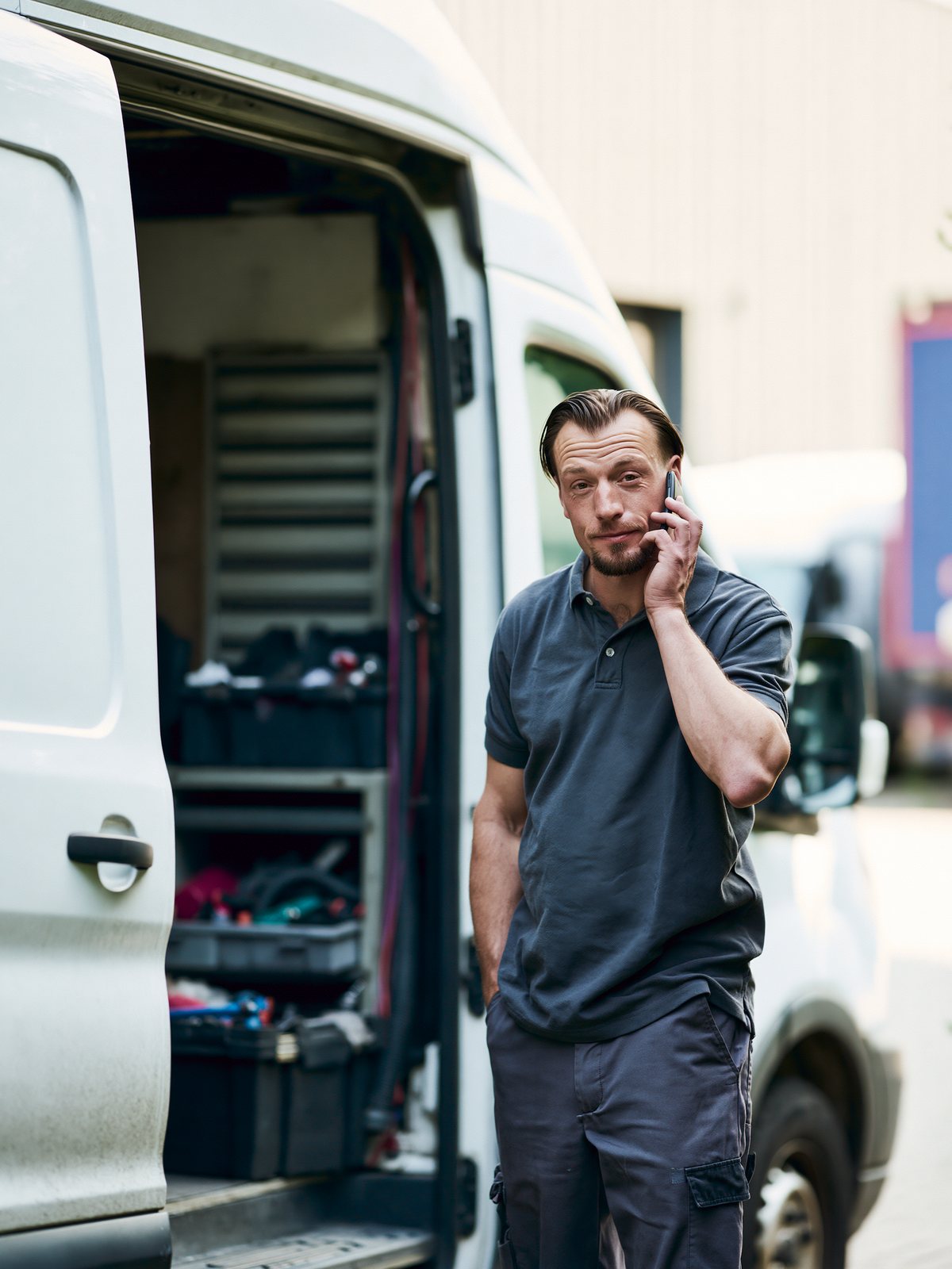 Field technician taking a call at the back of his van