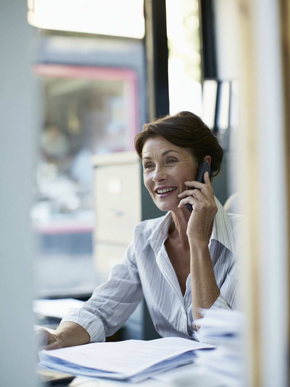 Insurance broker at her desk, checking a client file during a call