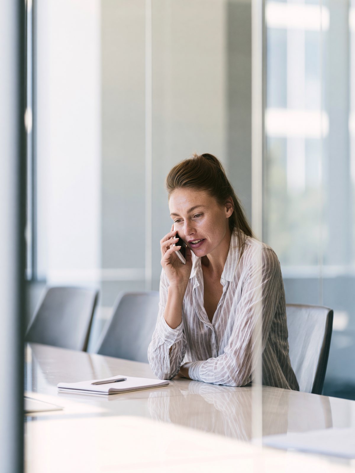 Recruiter at a meeting table, on the phone with a candidate