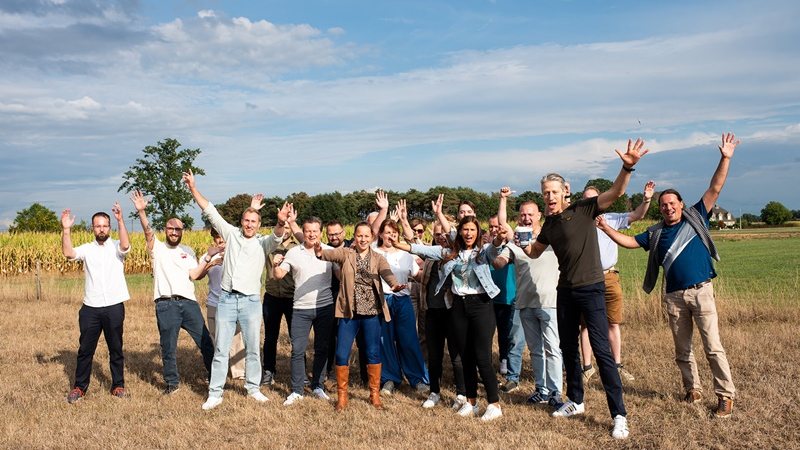The Telsmart team in a field in Kasterlee, hands in the air