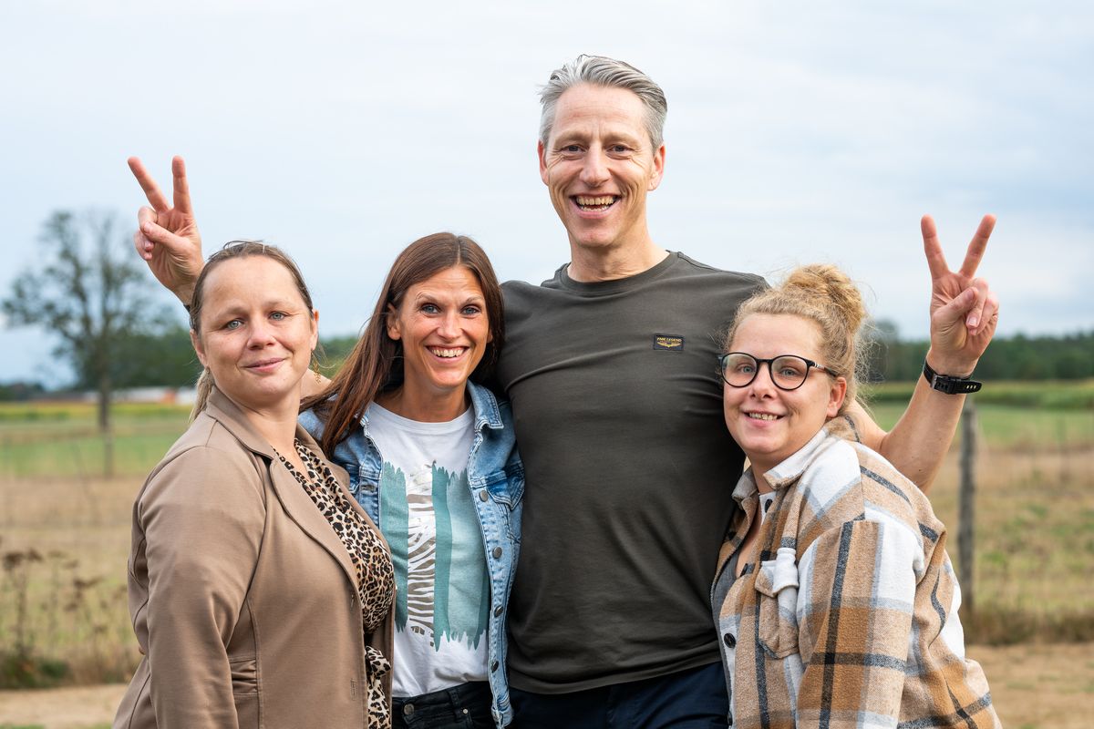Five Telsmart colleagues posing together in a field, two of them making peace signs