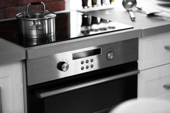 Modern electric stove with cooking utensils in a contemporary kitchen, featuring a sleek hob design and stylish domestic kitchen appliances.