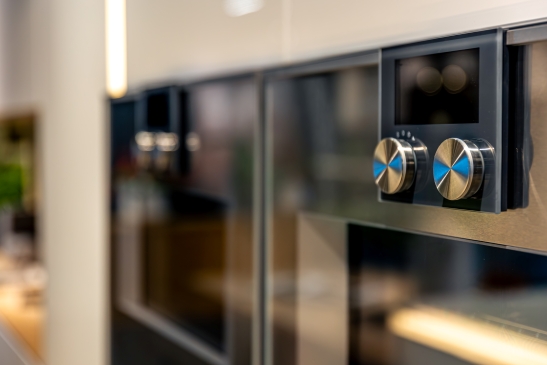 Built-in stainless steel oven with metallic control knobs in a modern kitchen, showcasing contemporary kitchen appliances and stylish interior design.