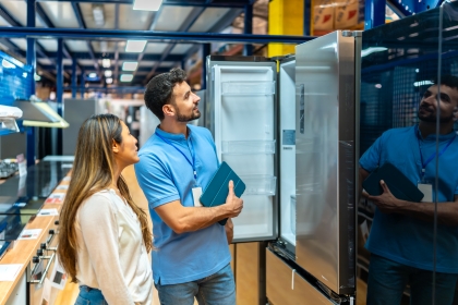 Sales assistant helping a customer compare refrigerators in an appliance showroom Bristol, showcasing quality domestic appliances and white goods for modern homes.