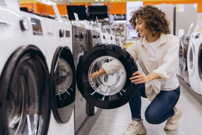 Woman viewing a washing machine in a Bristol appliance showroom while choosing domestic appliances.