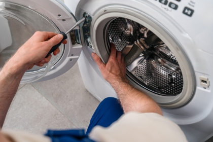 Washing machine engineer carrying out a repair on the door of a front-loading washing machine.
