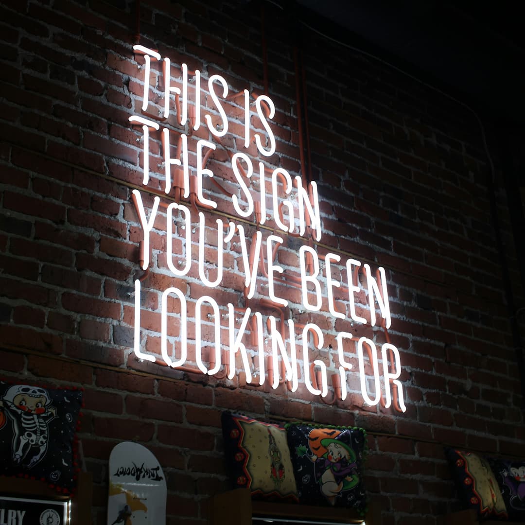 Neonbord met tekst 'This is the sign you’ve been looking for' aan een bakstenen muur.