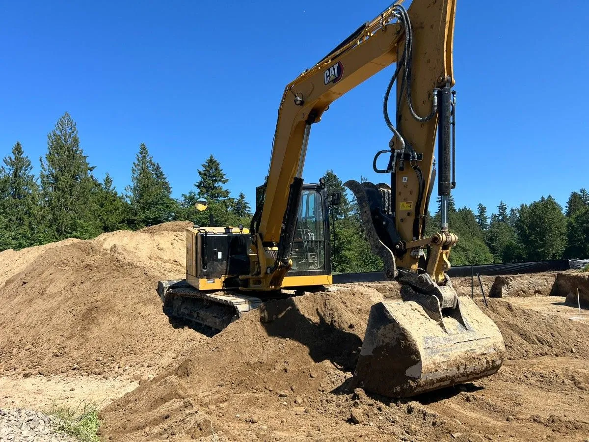 An excavator atop a cleared sloped lot for site preparation in Seattle