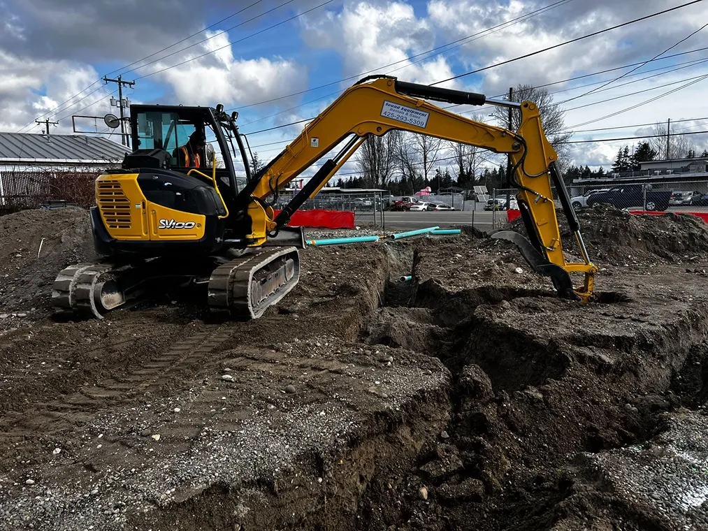 An operator digging trenches for water line installation in Seattle