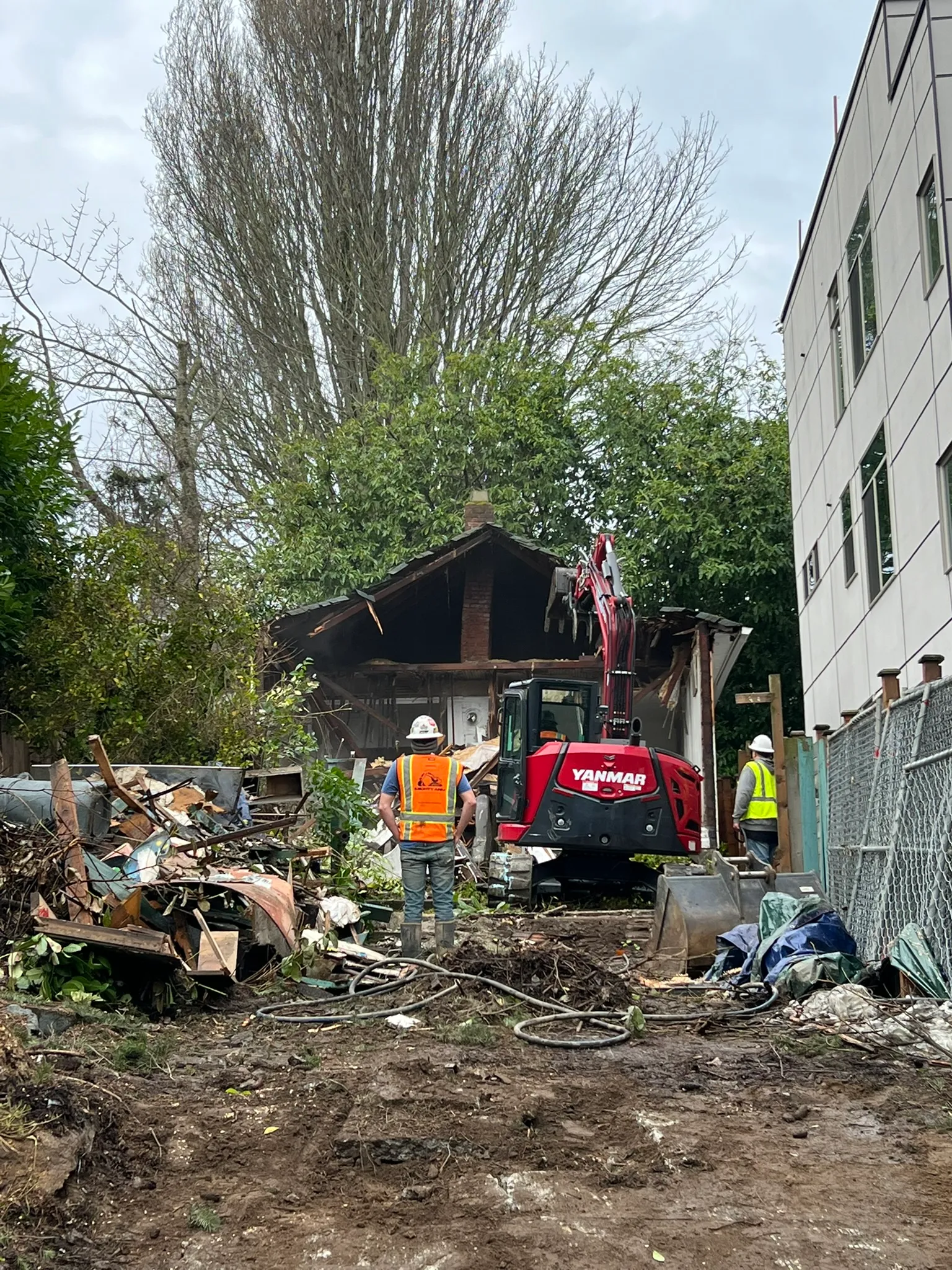 Contactors instructing excavator operator in demolishing an old home
