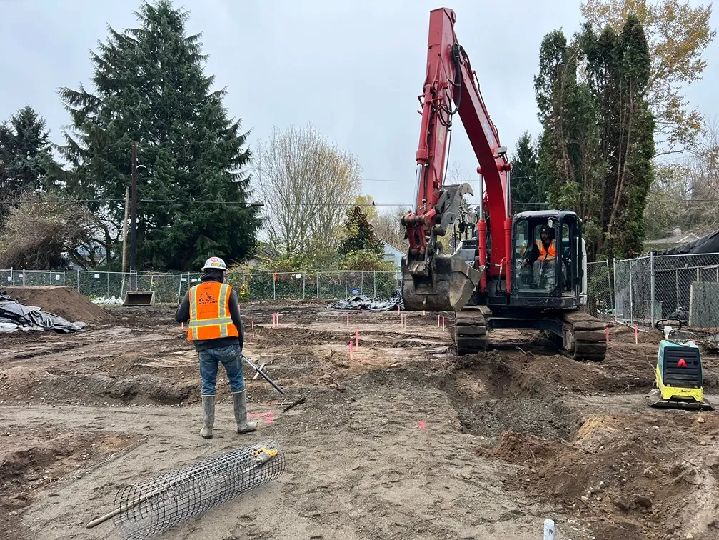 A contractor standing near an excavated trench in a job site in Seattle
