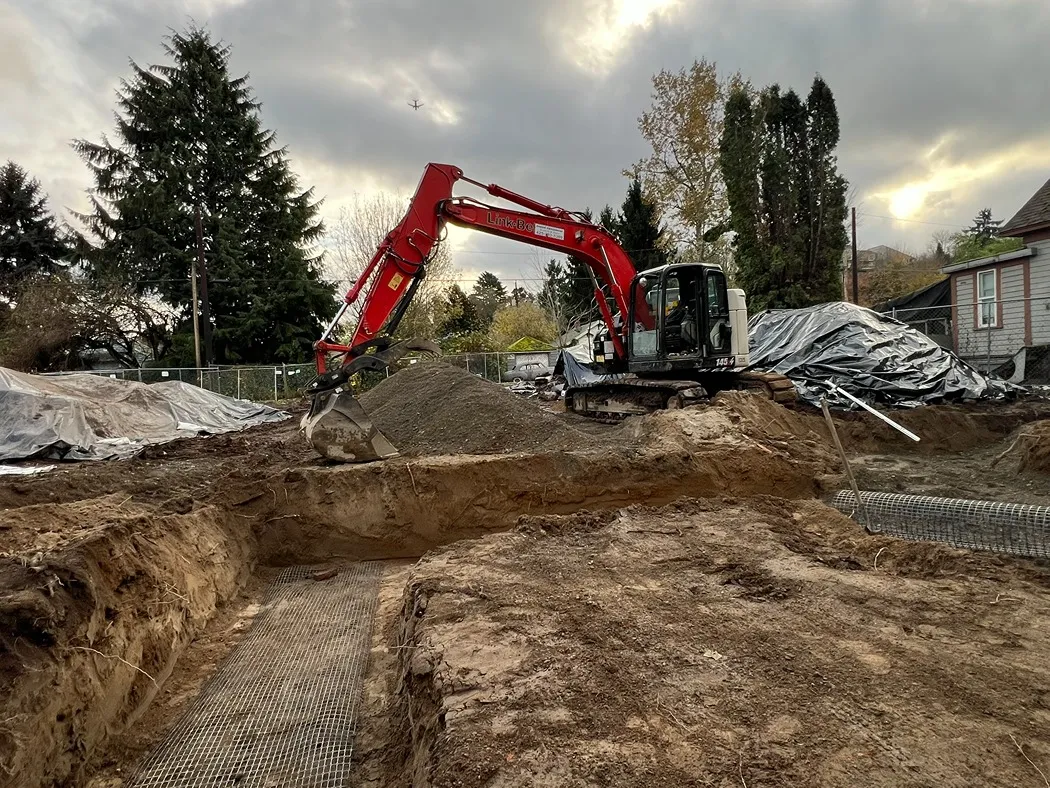 A lot in Seattle with open trenches and excavator during work