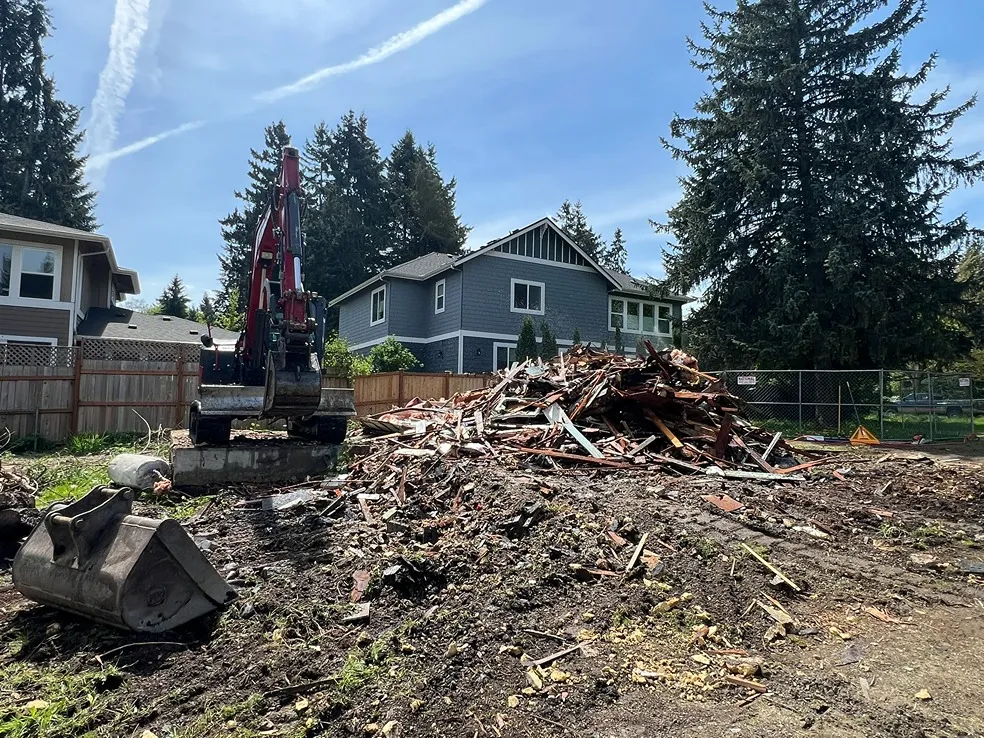 An excavator starting to collect debris from an old home demolition