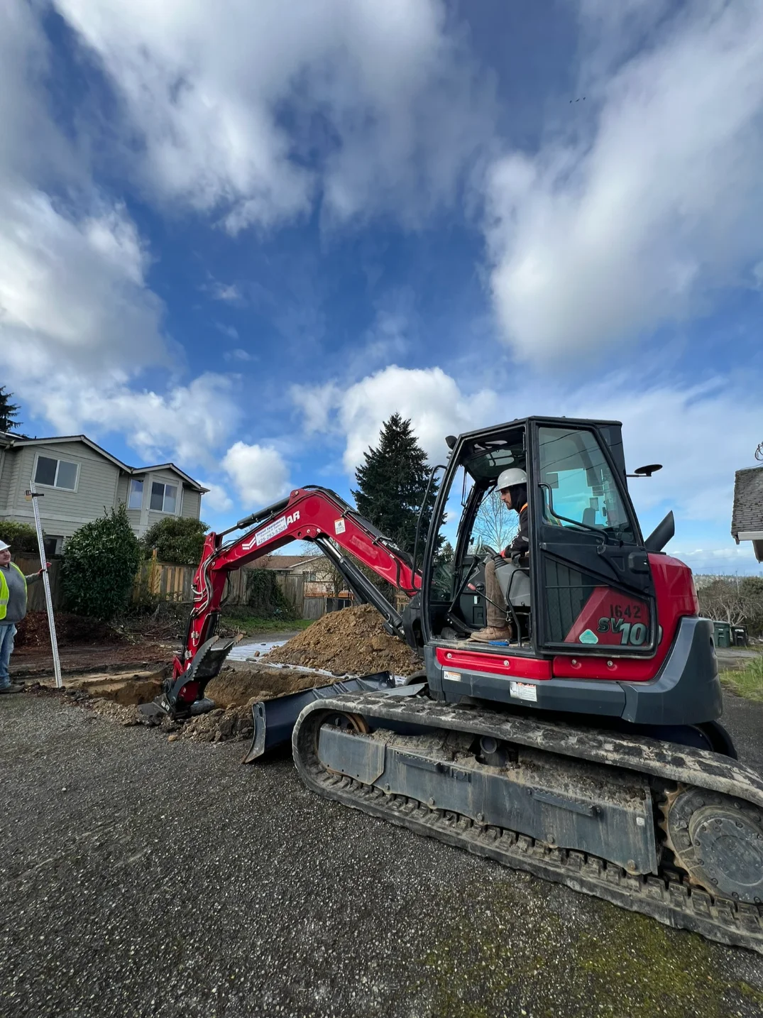 Excavator digging and grading a site near a residential development in Seattle 