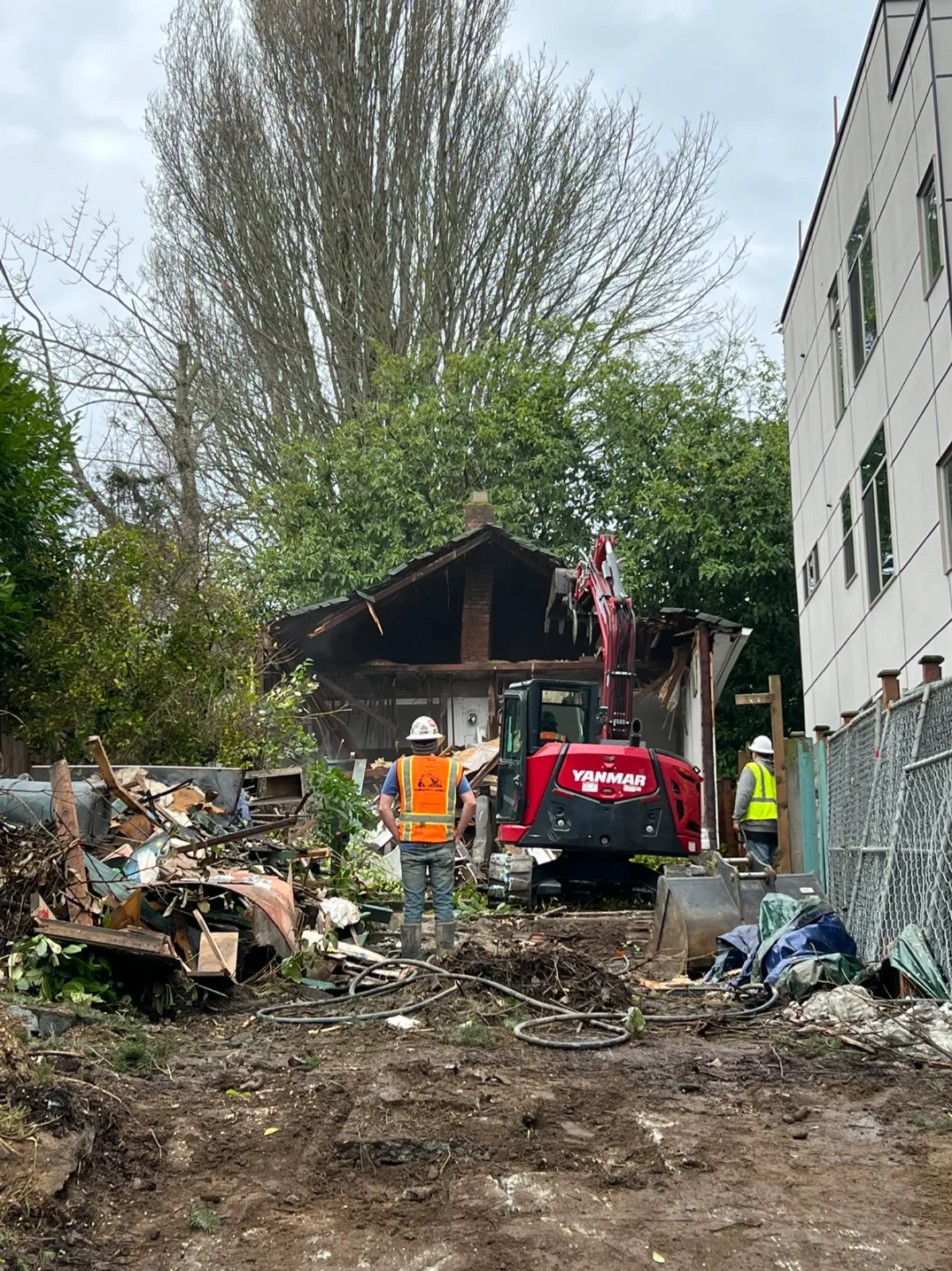 Contactors instructing excavator operator in demolishing an old shed