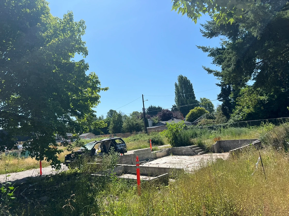 A vacant lot with an abandoned car and ruins of an old house in Seattle 