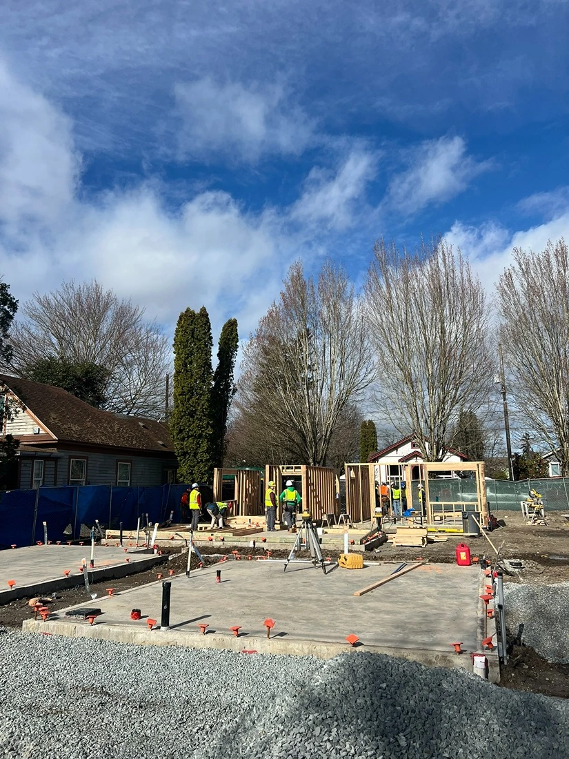 Contractors building a frame of a wooden home in a newly backfilled foundation in Seattle