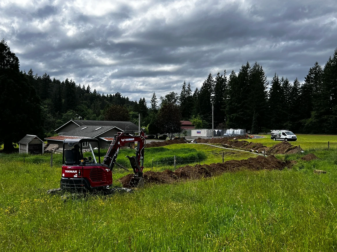 A contractor operating an excavator for utility installation trenches