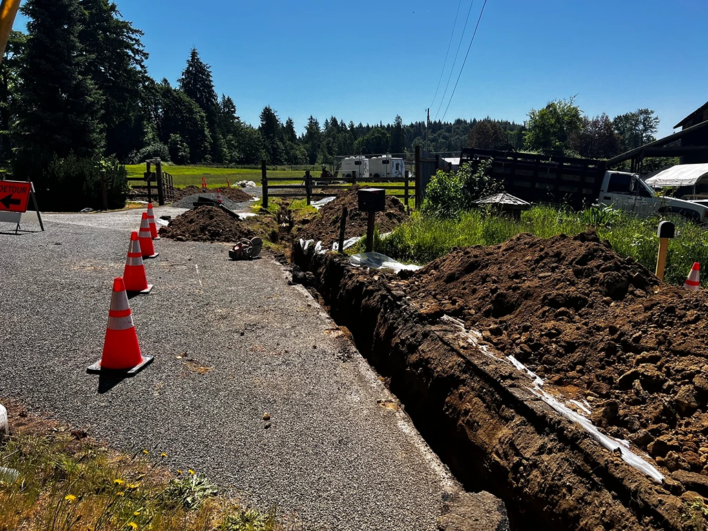 A trench near the side of a road for sewer line installation