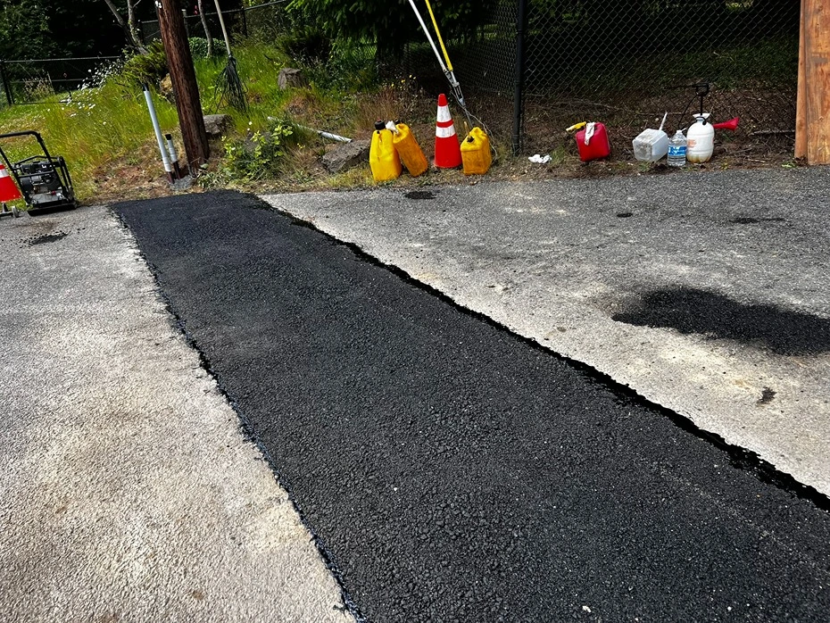 Freshly paved asphalt patch over a backfilled electrical trench