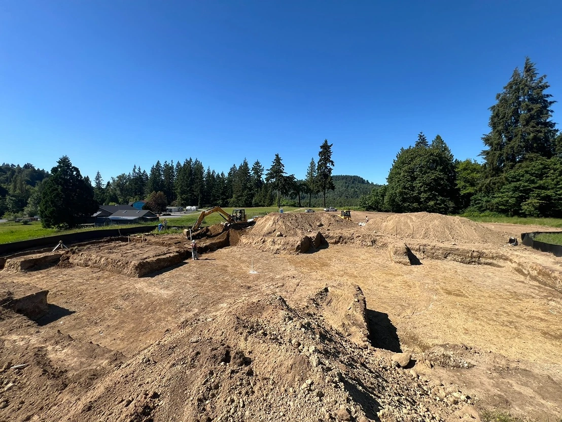 Mass excavation with piles of soil and debris in an open lot in Seattle