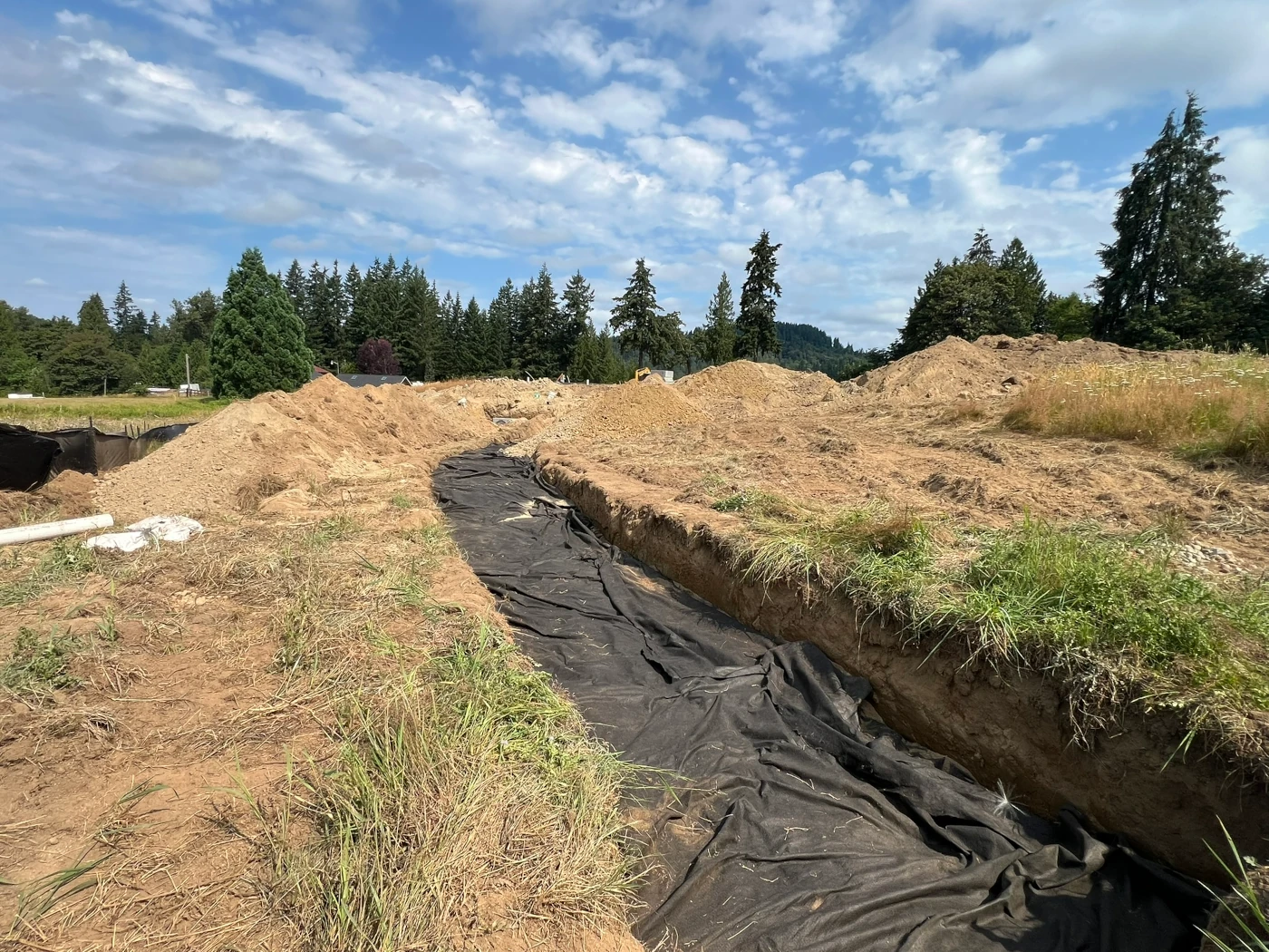 Infiltration trench lined with filter fabric before drain rock placement on a residential site